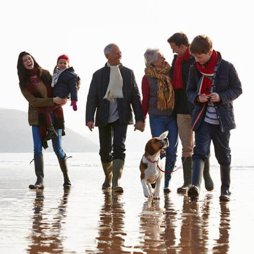 Multi-generation family walking on winter beach