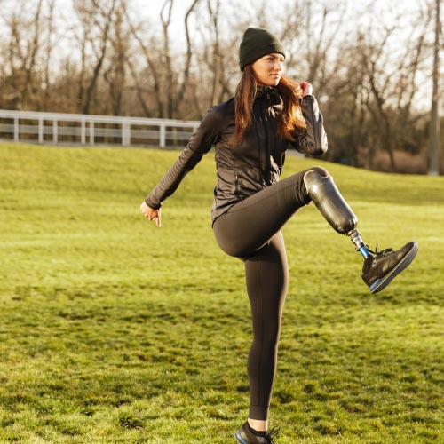 Woman raising prosthesis leg while exercising in the park