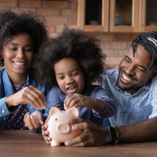 young family putting money into a piggy bank