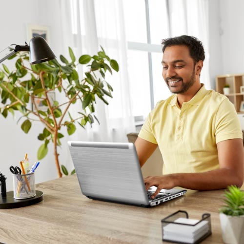 Man smiling working on a laptop from home