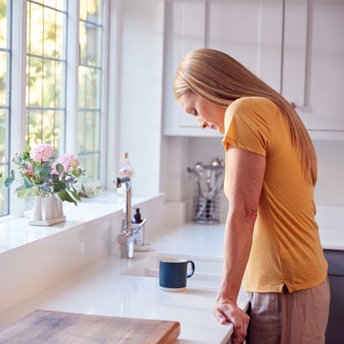 sad woman standing by the kitchen sink