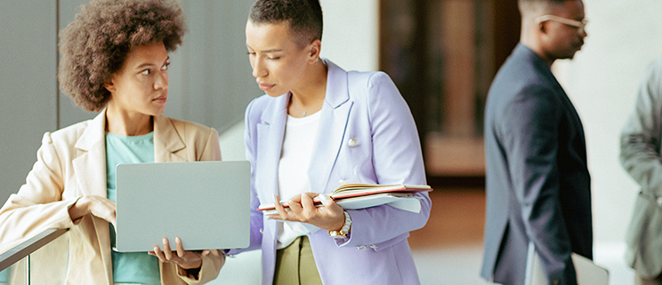 two ladies looking at a laptop having a conversation