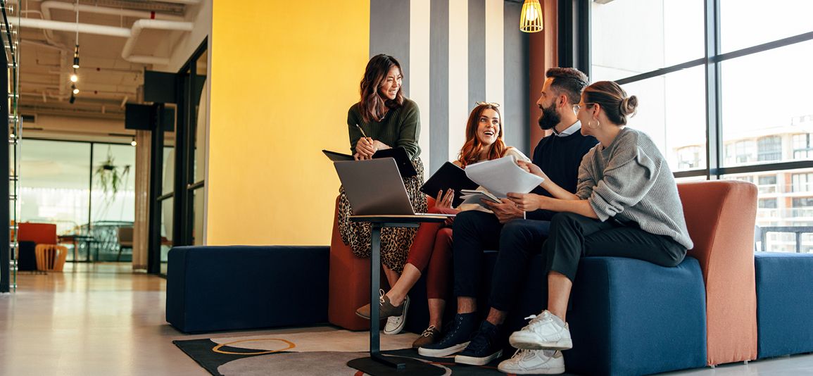 Group of happy businesspeople smiling while sitting together in a co-working space.