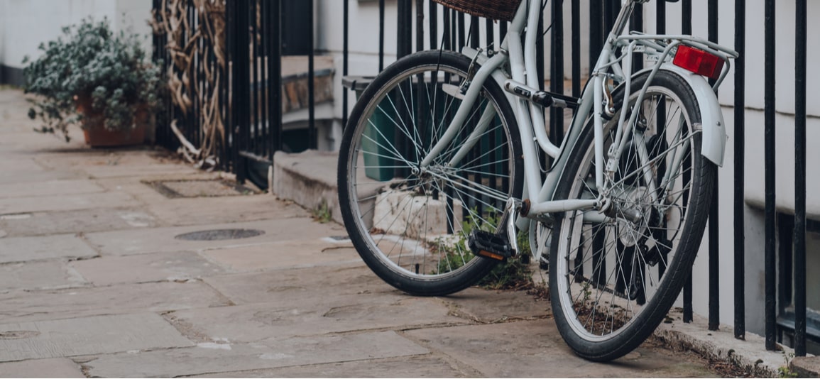 Bike chained to a metal fence outside a traditional terraced house in London