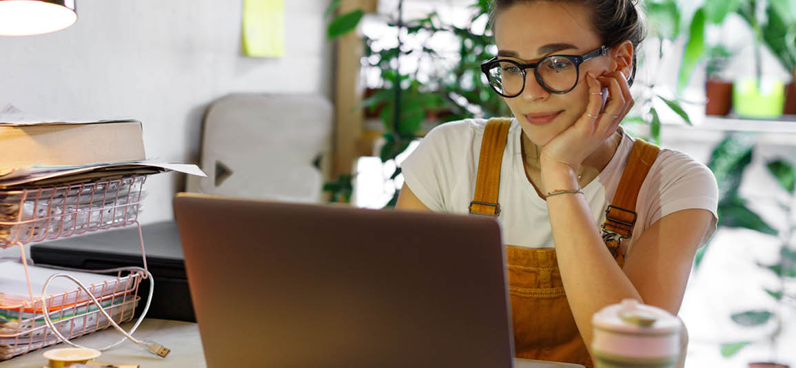 Close up on a woman using a laptop with a smile on her face