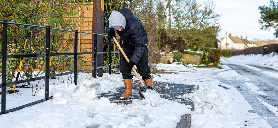 Man shovelling snow off a path to clear for pedestrians