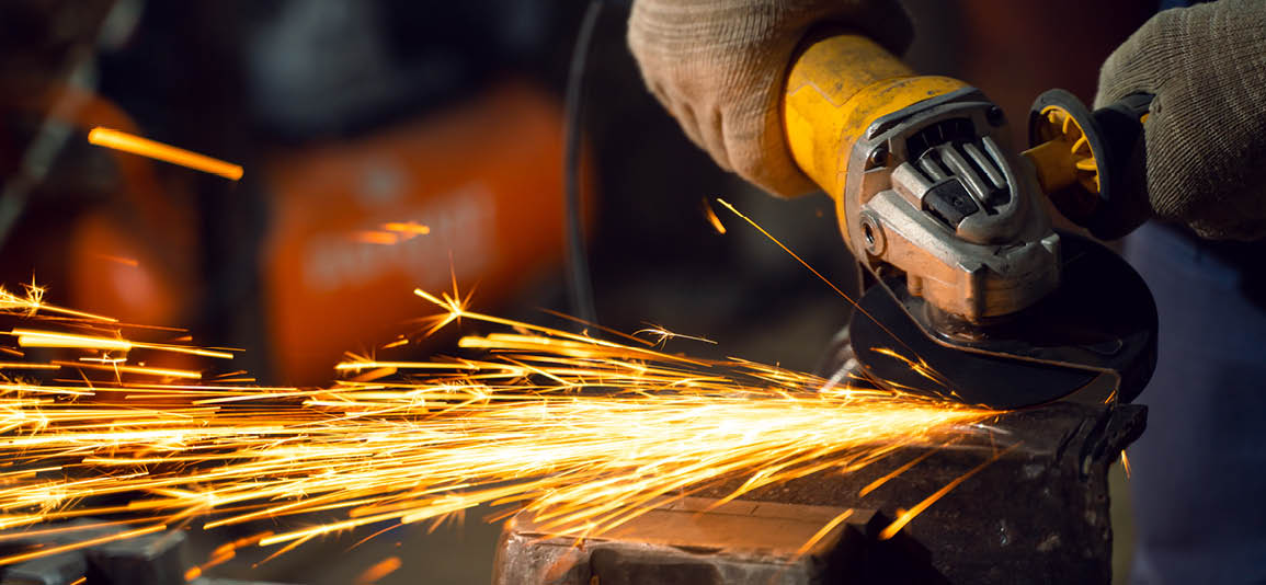 Close up of an angle grinder being used with sparks facing away from the user