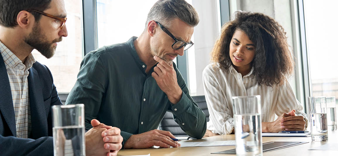 Man in middle of 2 legal advisors thinking about signing a legal document