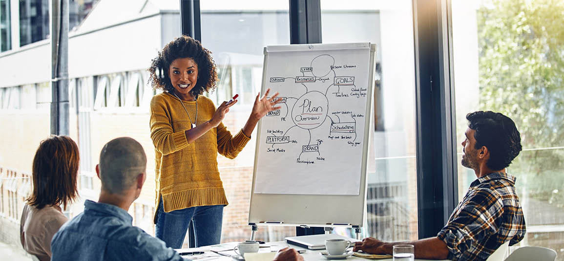  person standing and presenting to a small group in a modern office setting