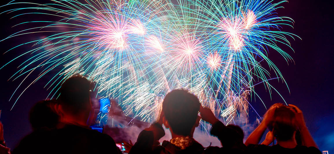 Group of people watching fireworks display at an event with their backs to the camera