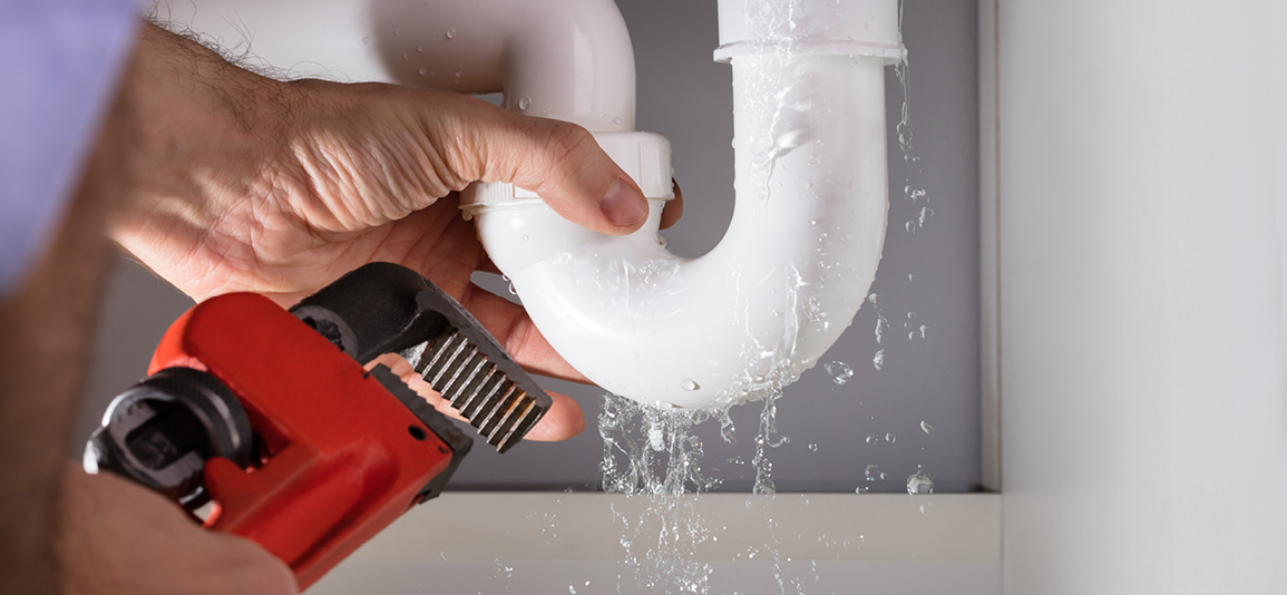 Close-up Of Male Plumber Fixing White Sink Pipe With Adjustable Wrench