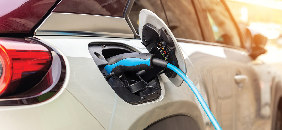 Close-up modern electric plug-in hybrid car parked near fast charger charging station