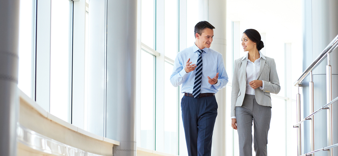Confident business partners walking down in office building and talking