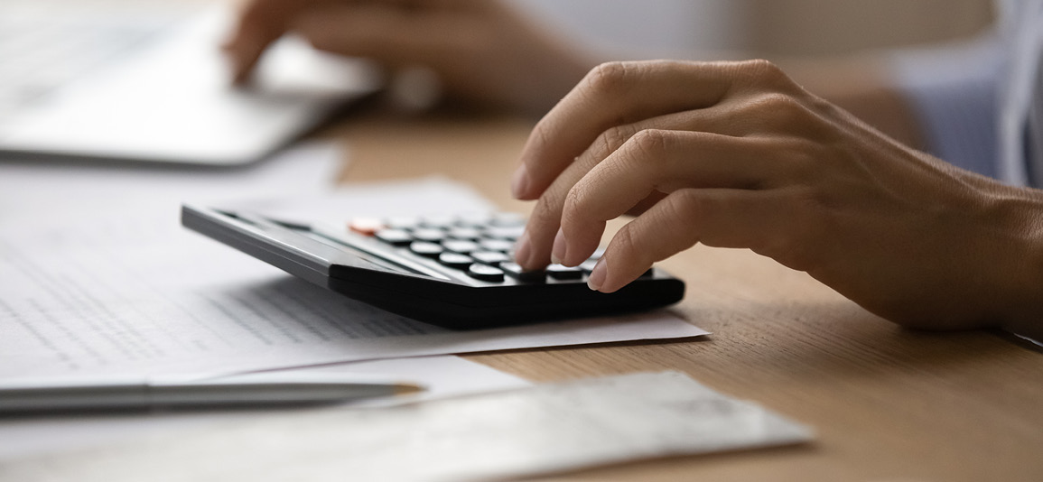 person using a calculator to work out bills
