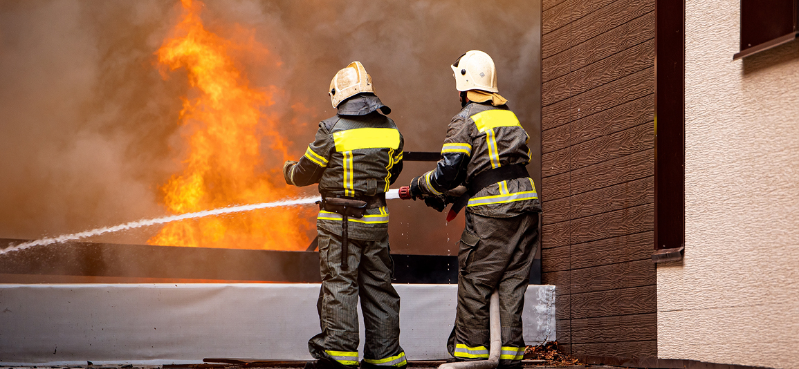 Action photo fireman team extinguishes burn with hose water.