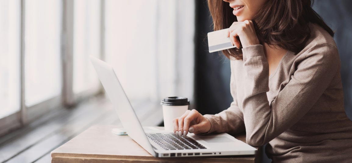Young woman holding credit card and using laptop