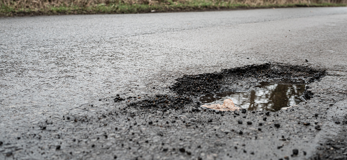Deep road pothole filled with rainwater.