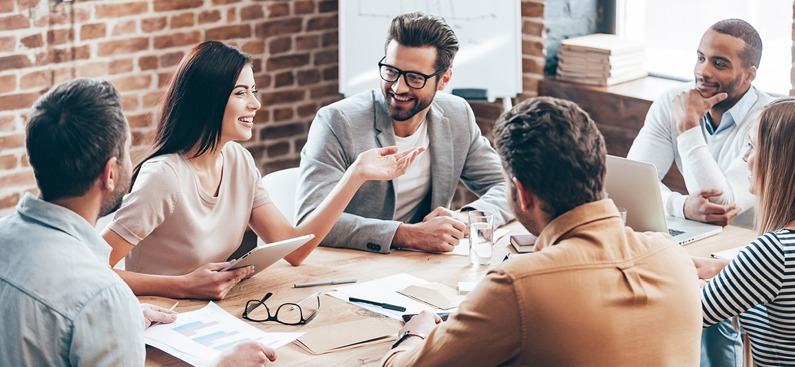 young woman addressing colleagues at desk in office