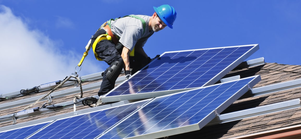 Man installing alternative energy photovoltaic solar panels on roof