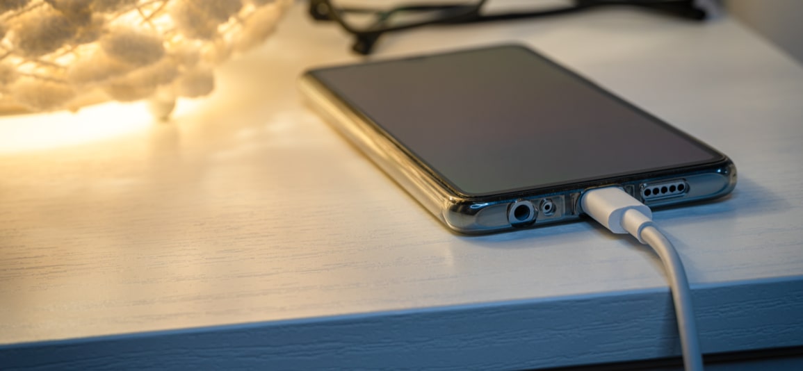 Smartphone charging with energy bank on nightstand at night