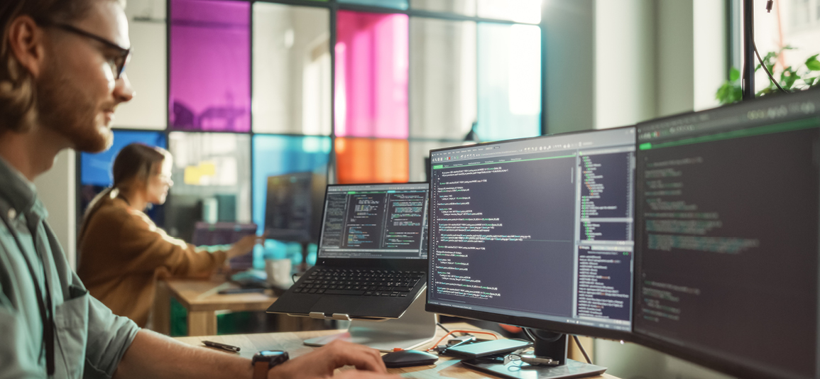 Male Programmer Coding on Desktop Computer With Two Monitors Set Up