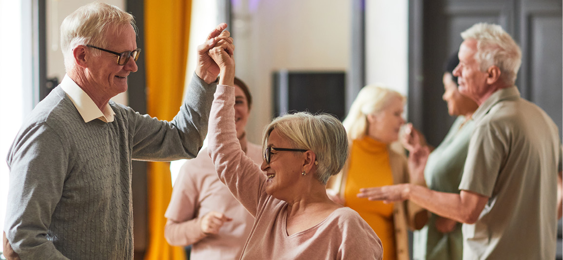 Senior citizens holding hands dancing in group