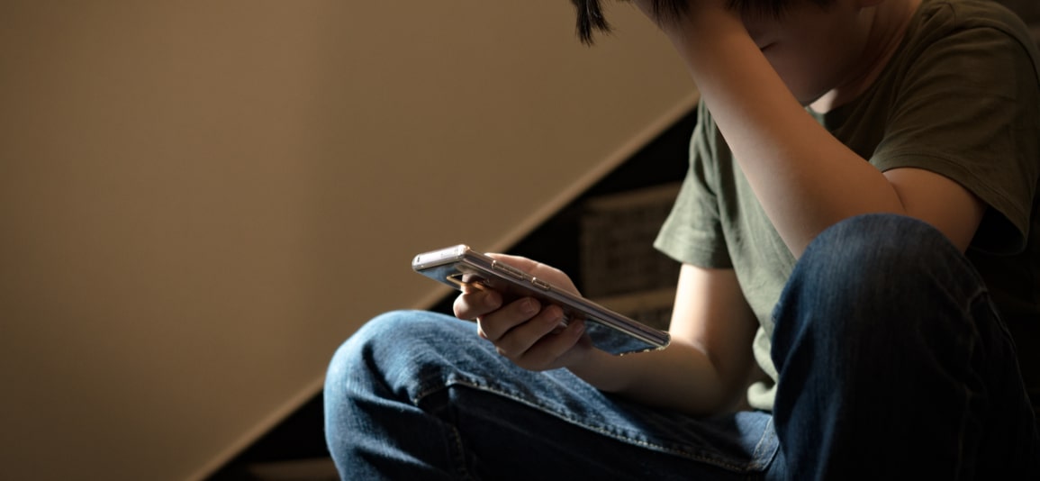 young boy upset holding phone