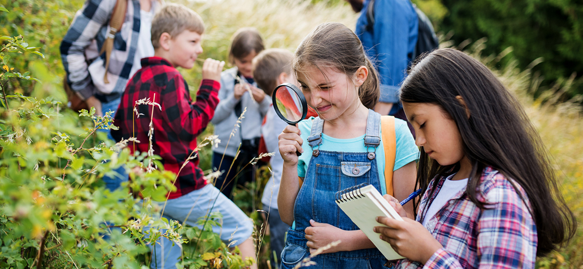 Group of school children with teacher on field trip in nature, learning science