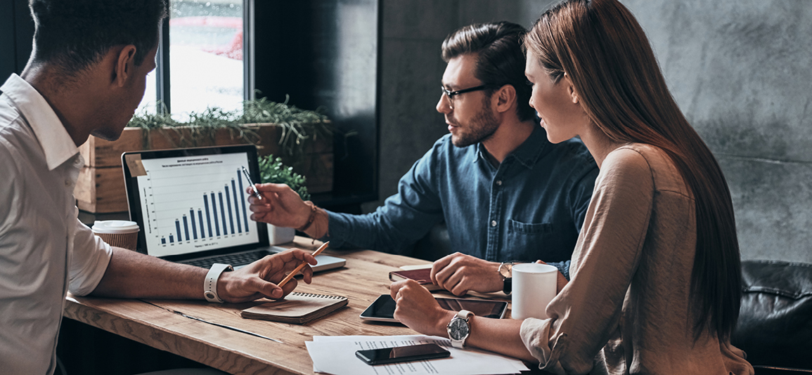 Group of young confident business people analyzing data using computer while spending time in the office