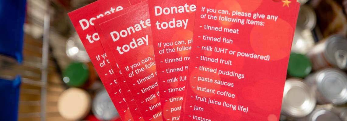 Donation leaflets for a food bank over a trolley of tins