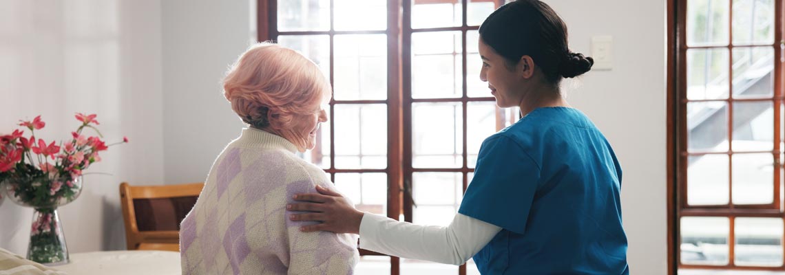 Comforting nurse with senior woman in nursing home