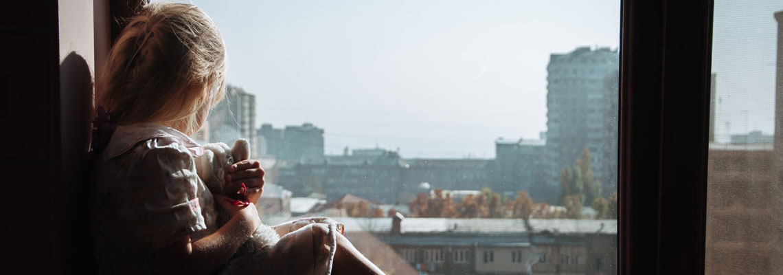 A girl with a toy is sitting on the windowsill