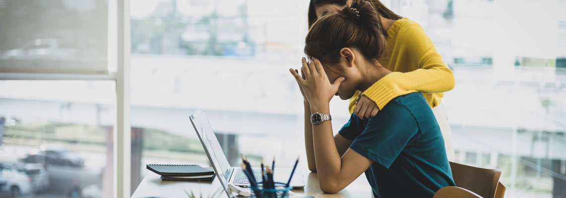 Co-worker comforting stressed woman in office