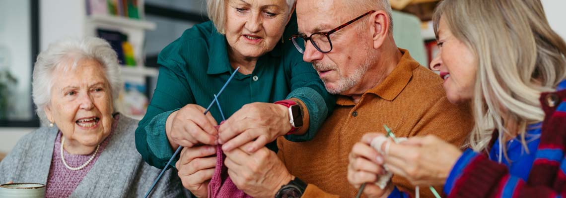 Group of senior people learning knitting together in a community center