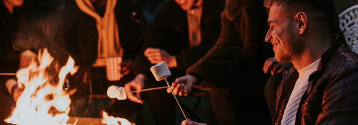 Friends enjoying s'mores and marshmellow together by the bonfire