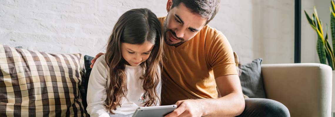 Little girl and her father using a digital tablet at home