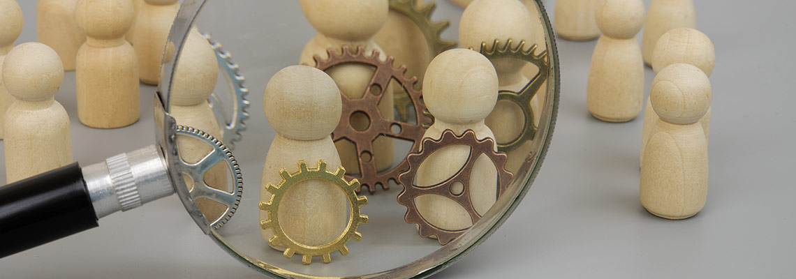 Wooden people figures under a magnifying glass