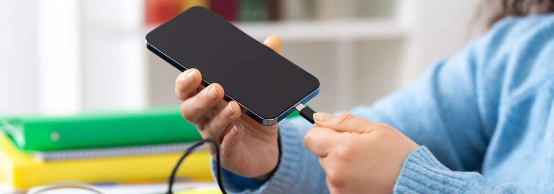 hand plugging charger cable to a smart phone at home