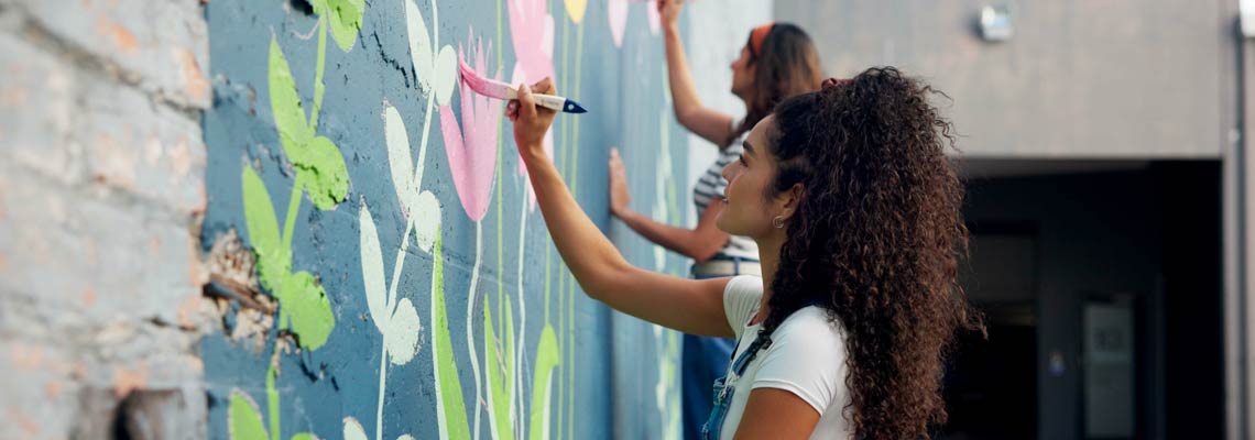 Girls painting colorful flowers on a wall together