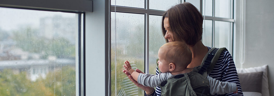 Mother and baby watching rain out the window