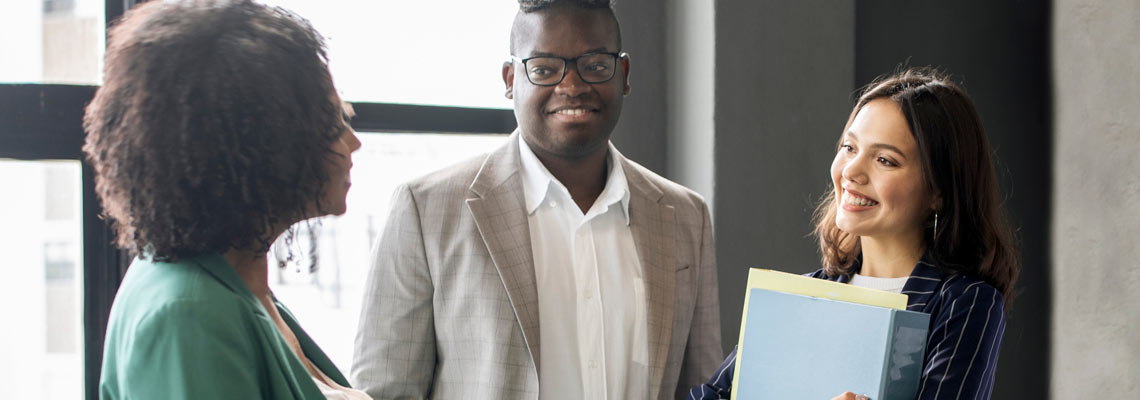 colleagues shaking hands while standing with manager
