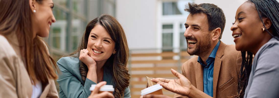 Happy young people talking and drinking coffee outdoors