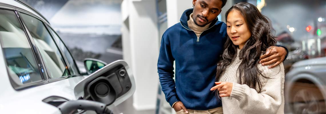 couple examining charging port of electric vehicle at car dealership