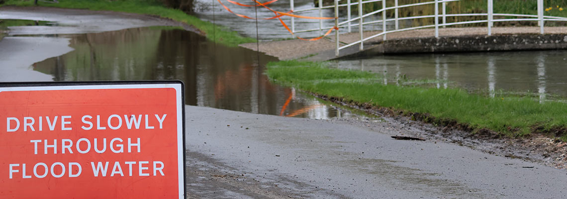 Flooded street with a flood warning sign