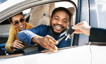 happy couple receiving the keys to their new car
