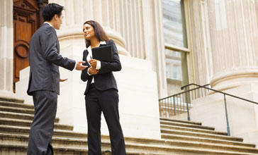 woman and man having a discussion on the stairs of a stately building