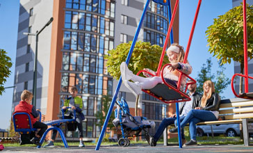 Parents sitting on bench while kids playing on playground
