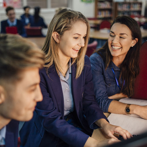 student is working with her teacher on the computer