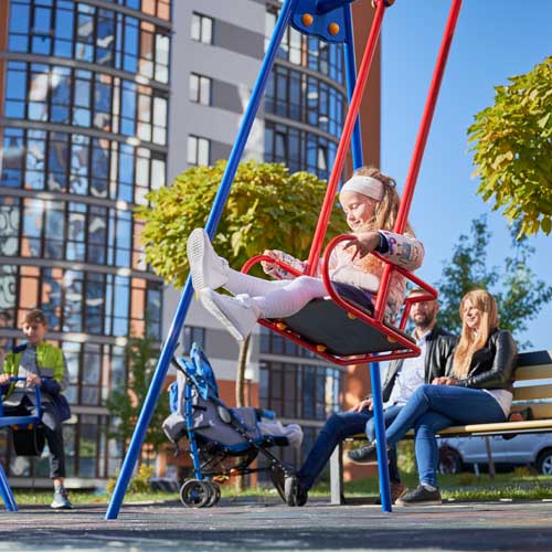 Parents sitting on bench while kids playing on playground